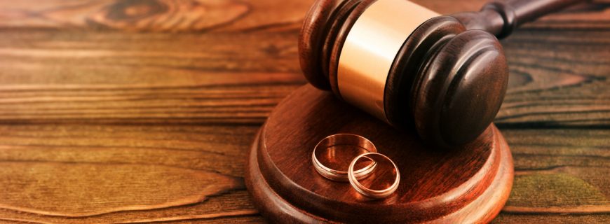 a pair of gold wedding rings, a judge's hammer on a wooden table background. family law
